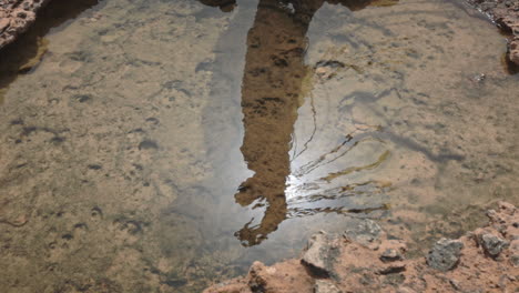 Reflejo-En-El-Agua-De-Una-Chica-Despreocupada-Con-Borlas-En-El-Viento