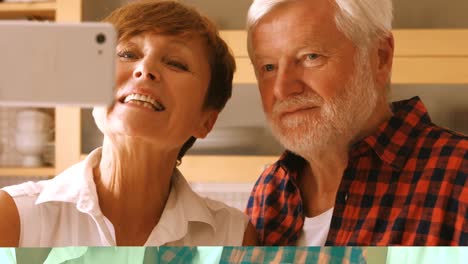 senior couple taking selfie on mobile phone in kitchen