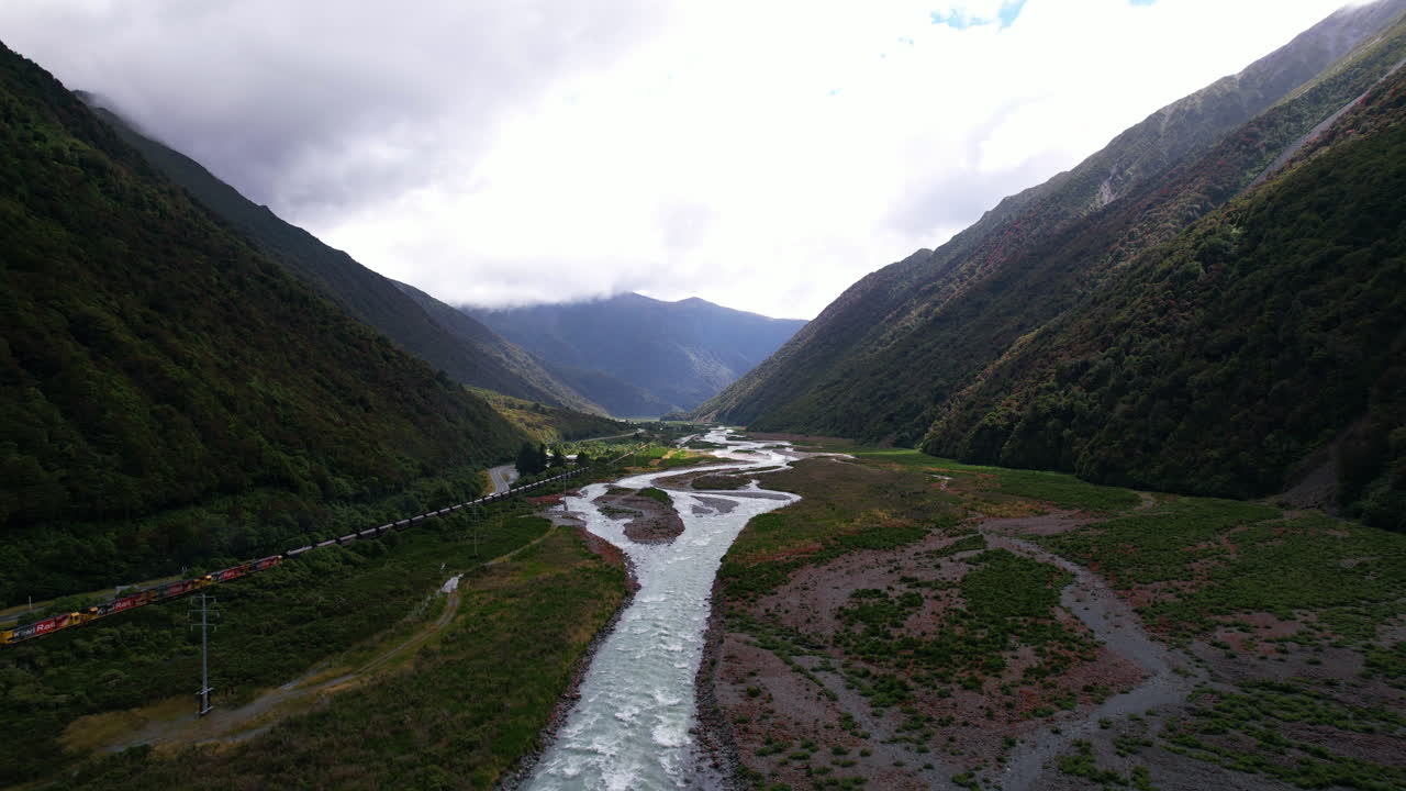 Aerial view of a train passing the Otira River Gorge, in cloudy New Zealand