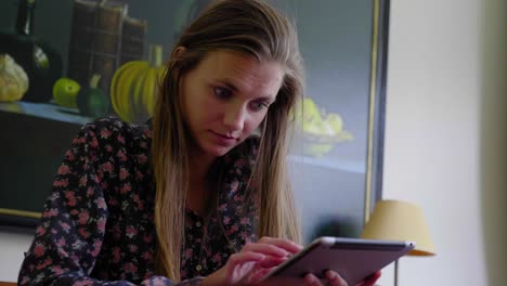 Young-woman-with-long-hair-works-on-tablet-at-home,-low-angle