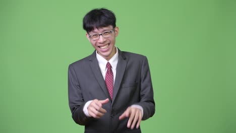 젊은 행복한 아시아 사업가 배를 들고 웃고