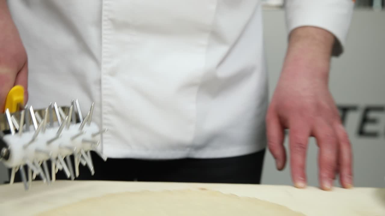 chef usando un rodillo puntiagudo para dar forma a la masa