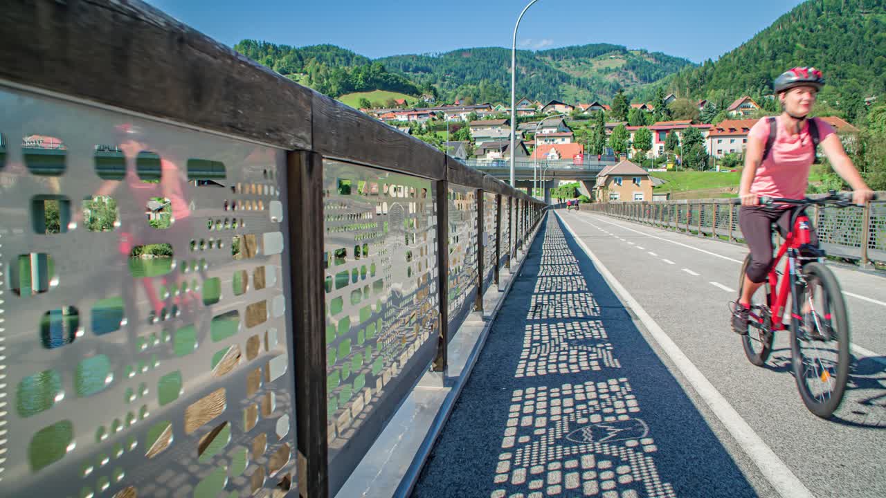 Slow motion shot of two young bikers riding along a bridge crossing a river in Slovenia