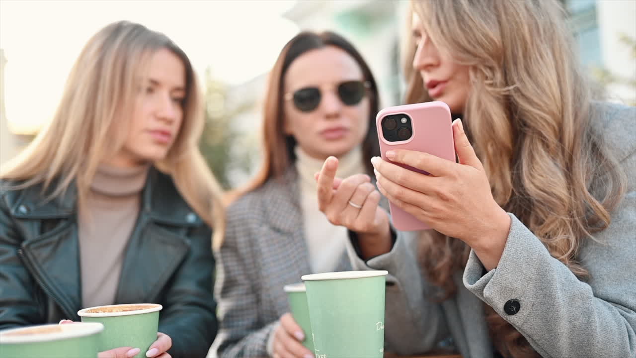 Three women going through a phone at a terrace