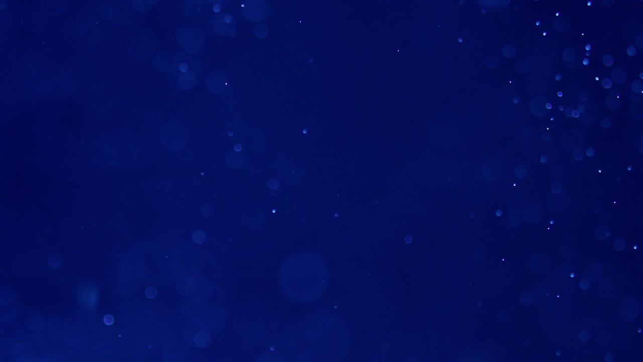 Abstract Shot of Air Bubbles Floating in the Water Against Deep Blue Background