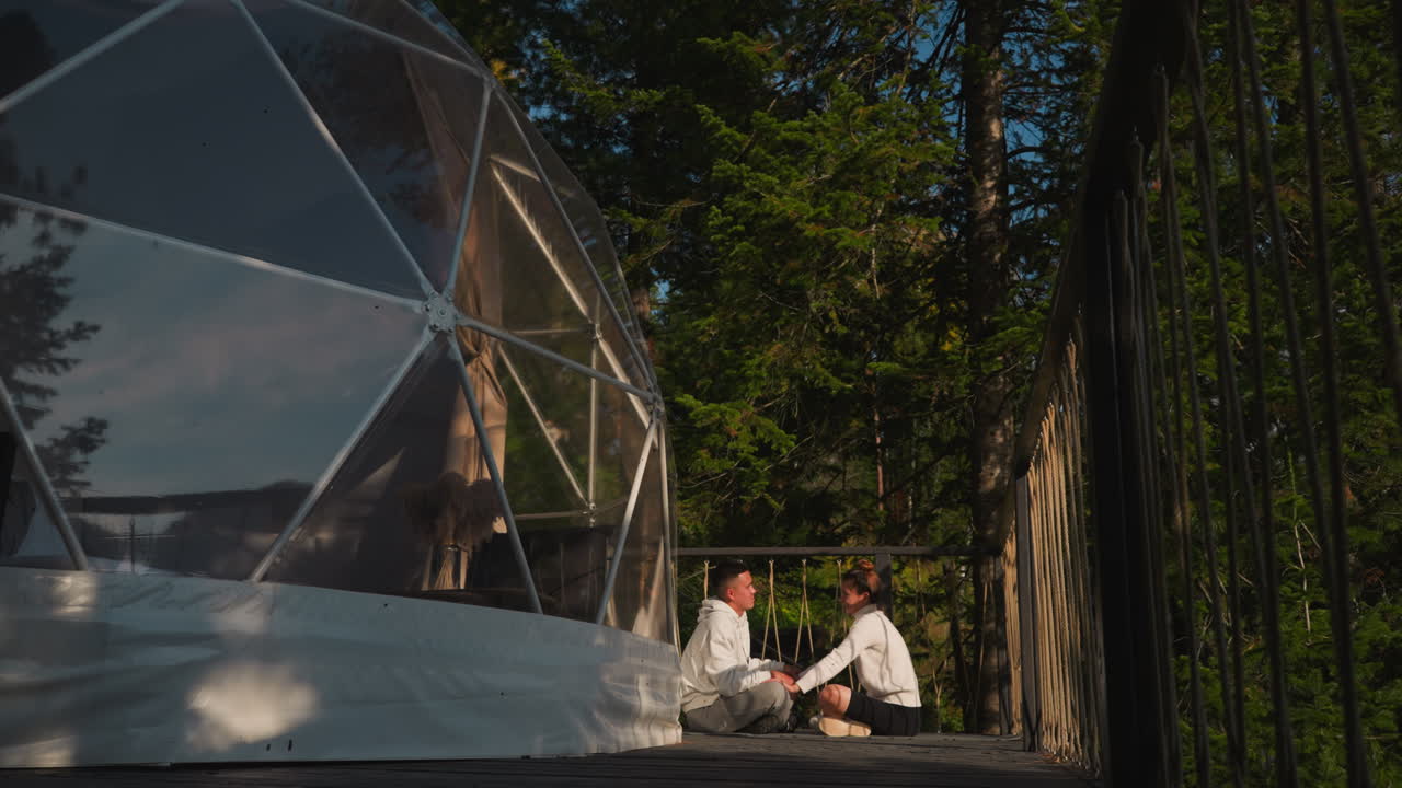 los recién casados hacen meditación de yoga cerca de la tienda por la mañana. los jóvenes disfrutan de la práctica del equilibrio sentados cara a cara en el eco-resort. concepto de vacaciones saludables