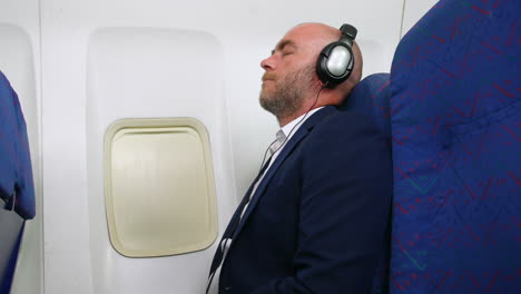 man relaxing listening to music wearing headphones traveling on a passenger airline plane