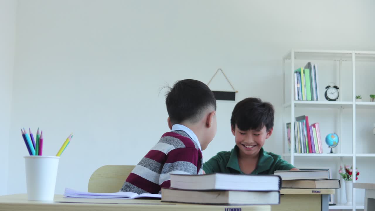 An Asian school boy giving a pencil to his friend in the class