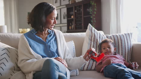 Young-African-American-mother-sitting-on-a-sofa-playing-with-her-three-year-old-son-at-home,-close-up