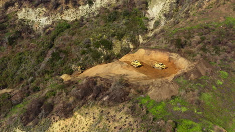 Dos-Excavadoras-Conduciendo-En-Un-Sitio-De-Construcción,-Lavado-De-Rat-Creek,-Big-Sur,-Nosotros,-Círculo-Aéreo