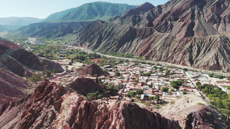 Drone-approaching-the-Seven-Colors-Mountain-and-unveiling-the-ancient-town-of-Purmamarca,-in-Jujuy,-Argentina