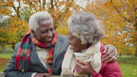 Portrait-of-loving-senior-couple-leaning-on-gate-on-walk-through-autumn-countryside-together---shot-in-slow-motion