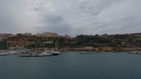 Aerial-view-of-a-beautiful-harbor-on-the-blue-sea-on-the-coast-of-malta-in-valletta,-overlooking-sailing-ships,-boats-and-historic-buildings-in-the-background-during-a-summer-trip-on-vacation