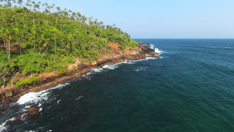 fpv rising up from sea over high green hill full of palm trees, sri lanka