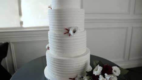 Elegant-3-tiered-wedding-cake-in-slow-motion-with-beautiful-red-flower-bouquet-and-server-set