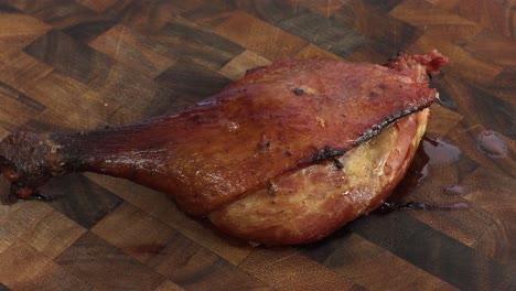 muslo de pato confitado asado, girando la vista en una tabla de cortar de madera