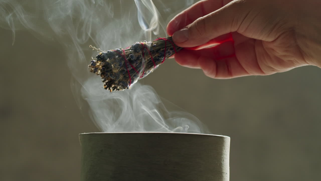 Person holding Palo Santo wood stick in hand, aromatic Palo Santo burning on black background, smoke spreading around, slow motion video clip, high quality 4k close up footage. High quality 4k footage