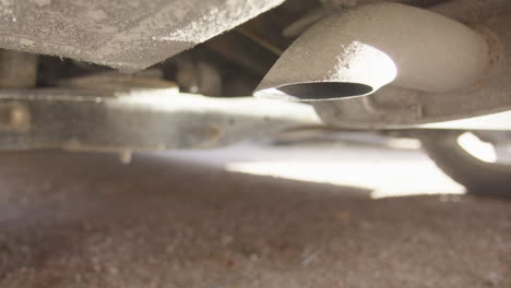 zoom in - a smoking exhaust as the car sits engine idling. air pollution