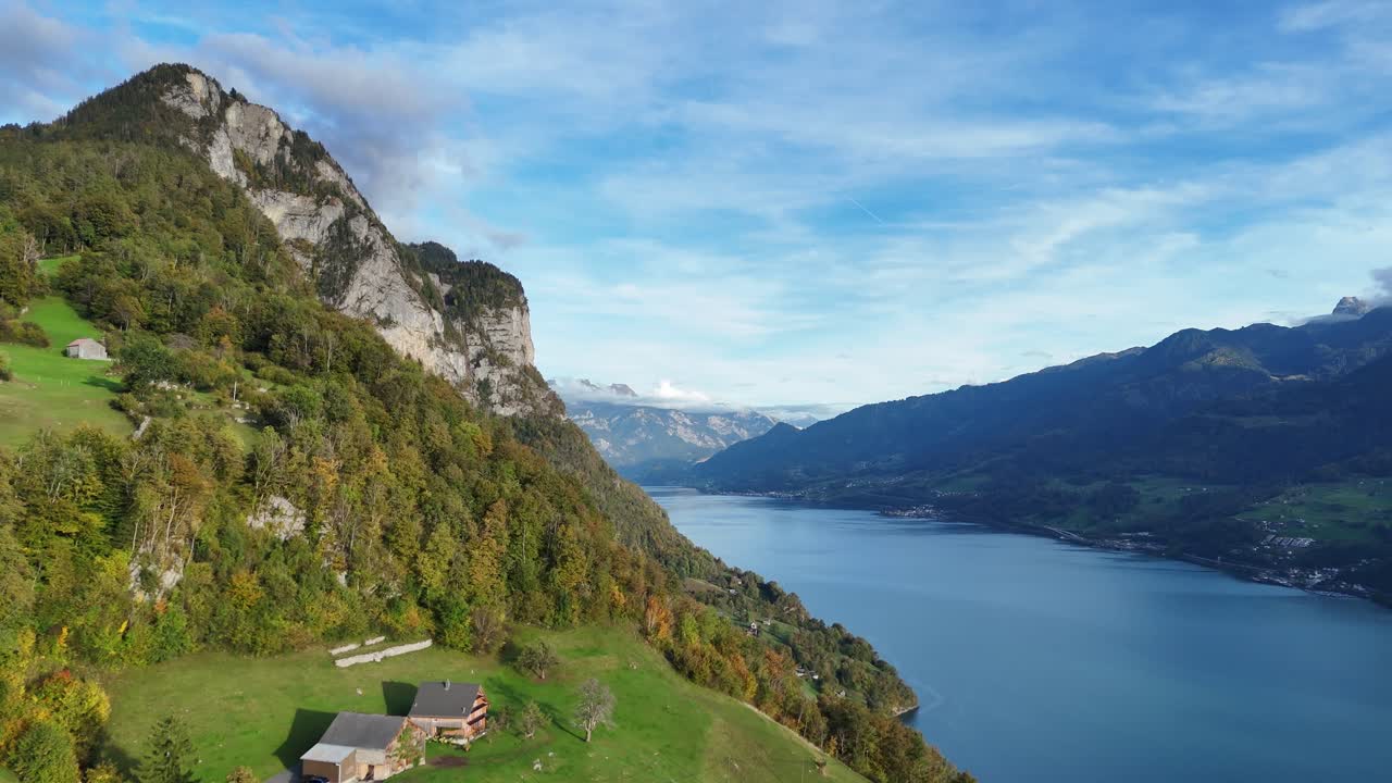 vuelo aéreo hacia atrás que muestra montañas verdes con casa con vista al lago walensee en amden, suiza durante la hora dorada