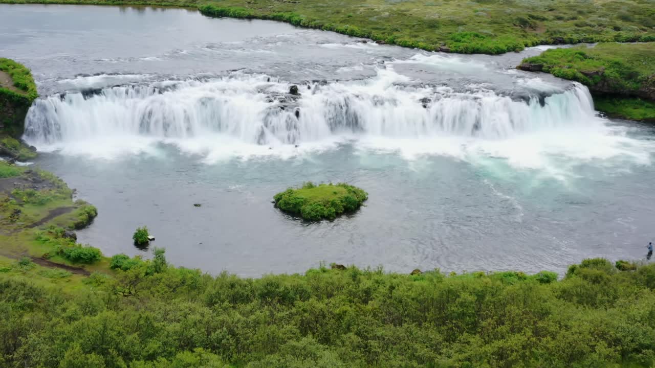 mujer caminando frente a una gran cascada