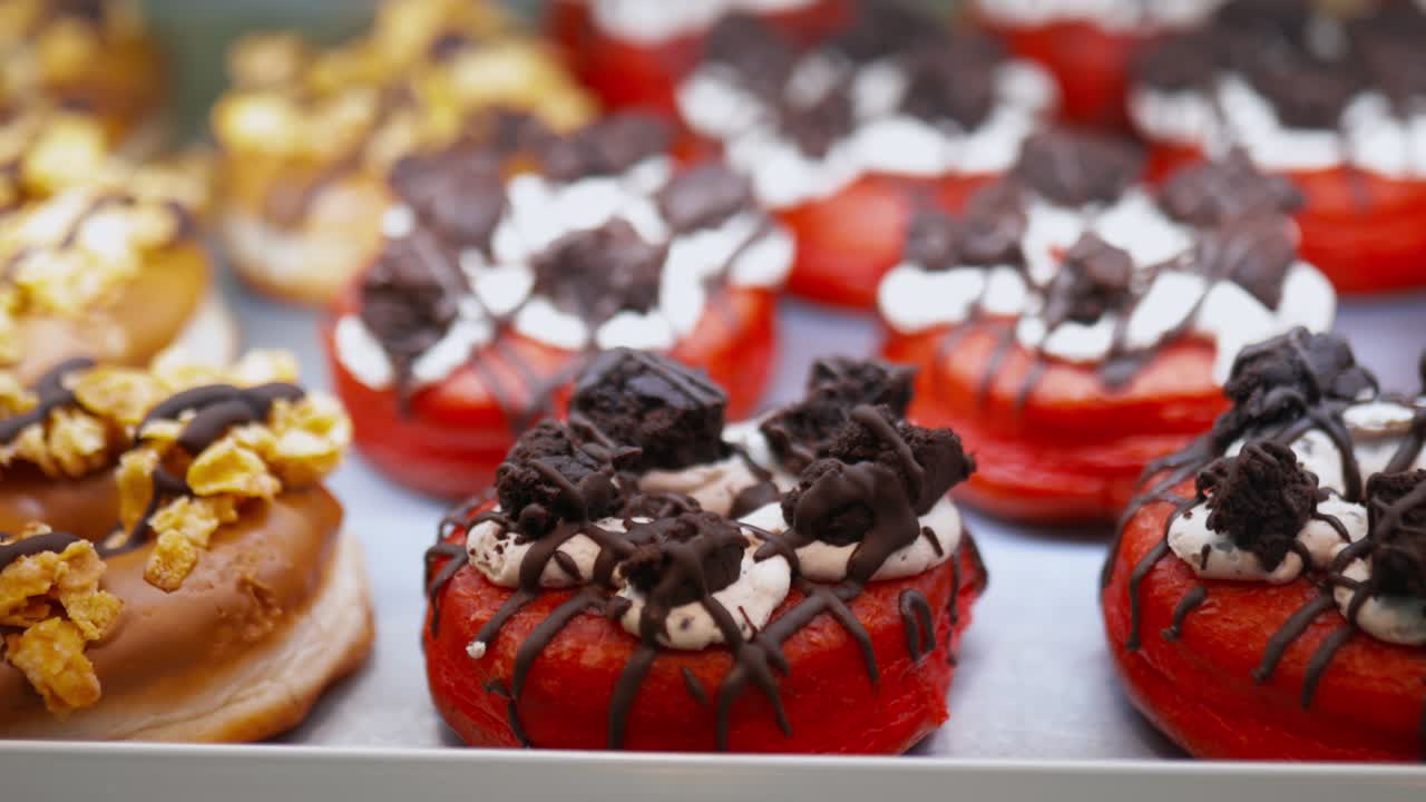 Red doughnuts covered with cookie crumbs and doughnuts covered with cornflakes