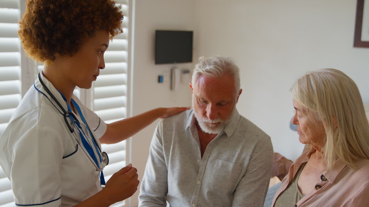 Female Nurse Wearing Uniform Giving Senior Couple Bad News In Private Hospital Room