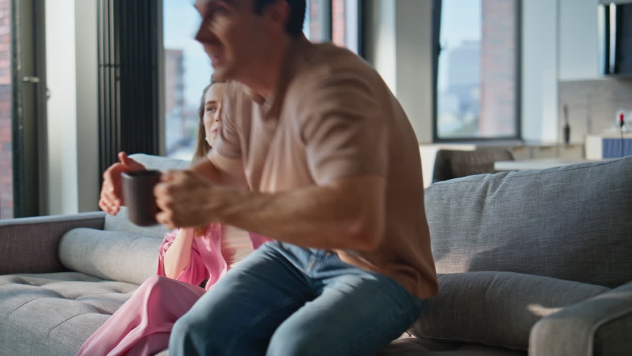 Caring husband bringing coffee to woman sitting on sofa cozy living room