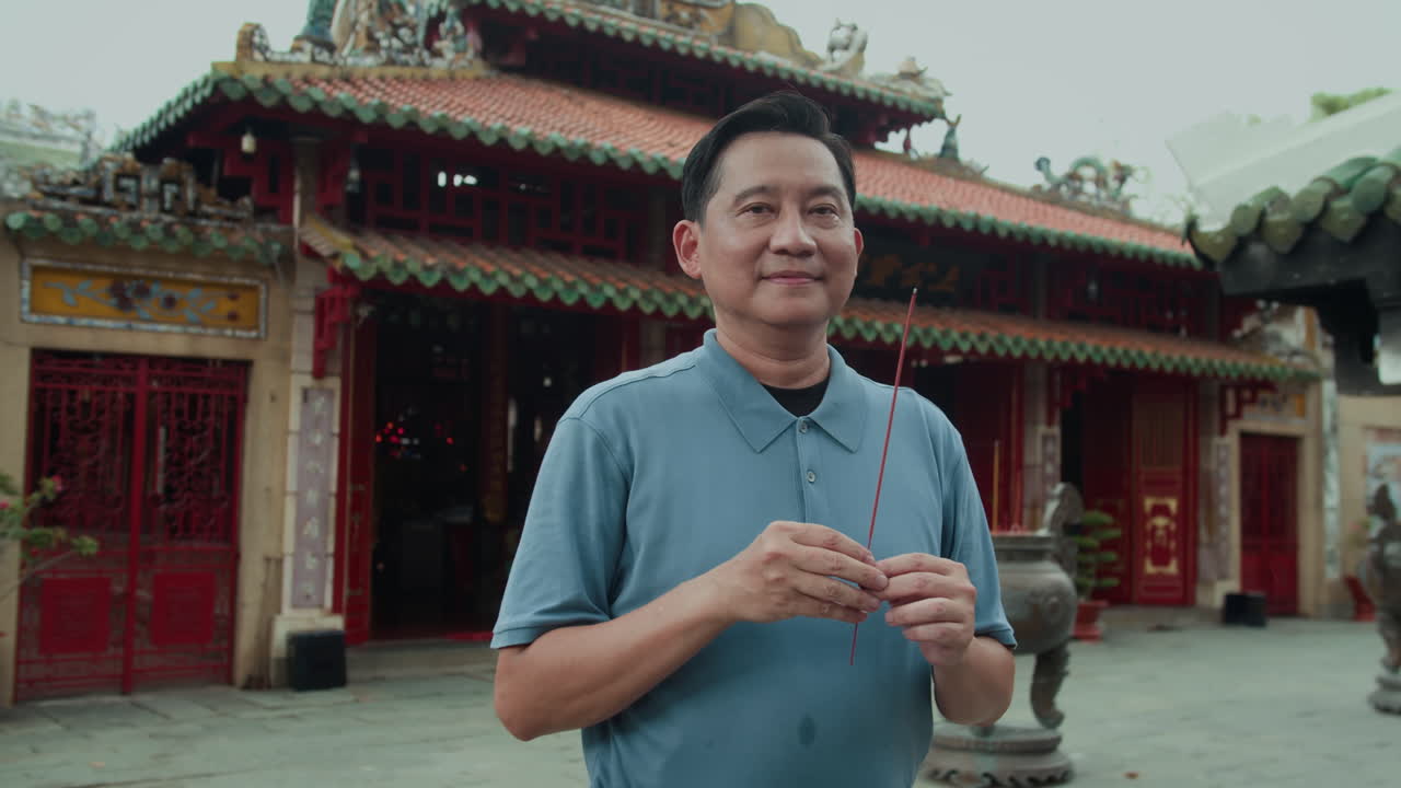 Portrait of Adult Asian Man Holding Burning Stick on Territory of Temple
