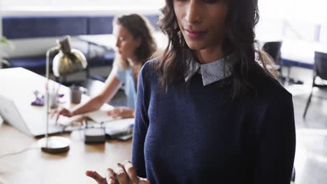 Portrait-of-happy-biracial-casual-businesswoman-using-tablet-in-office,-slow-motion