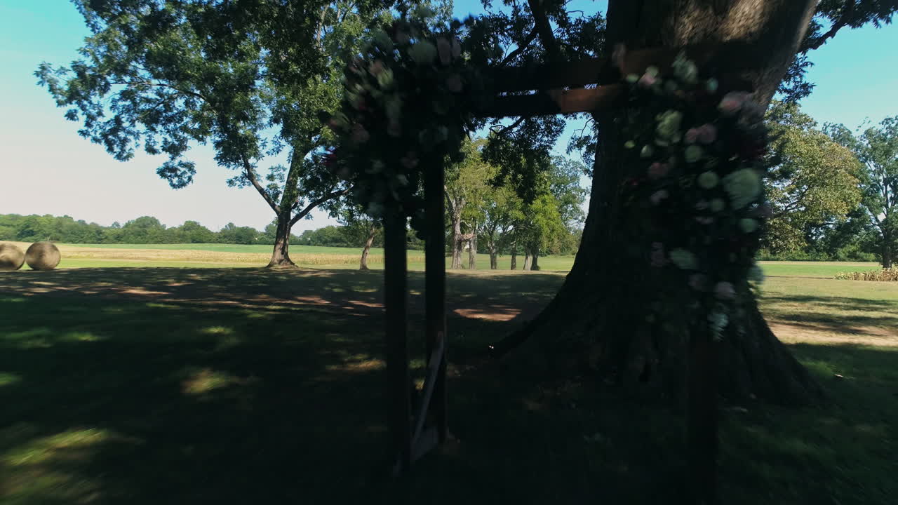 Low aerial view passing through alter of rural wedding venue under tree, 4K