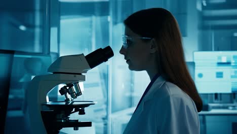 a scientist looking through a microscope in a lab