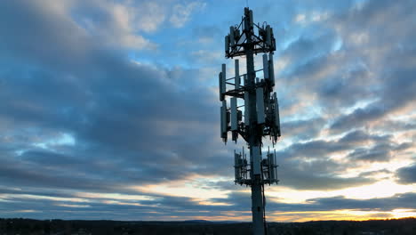 Aerial-of-cell-phone-tower-at-night-against-sunset-sky-in-American-town