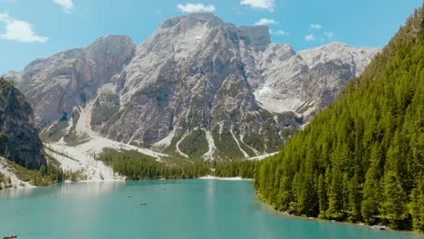 Toma-Aérea-De-Un-Dron-Sobre-El-Río-Con-Los-Alpes-Dolomitas-En-La-Parte-De-Atrás,-Lago-Di-Braies,-Italia,-Dolomitas