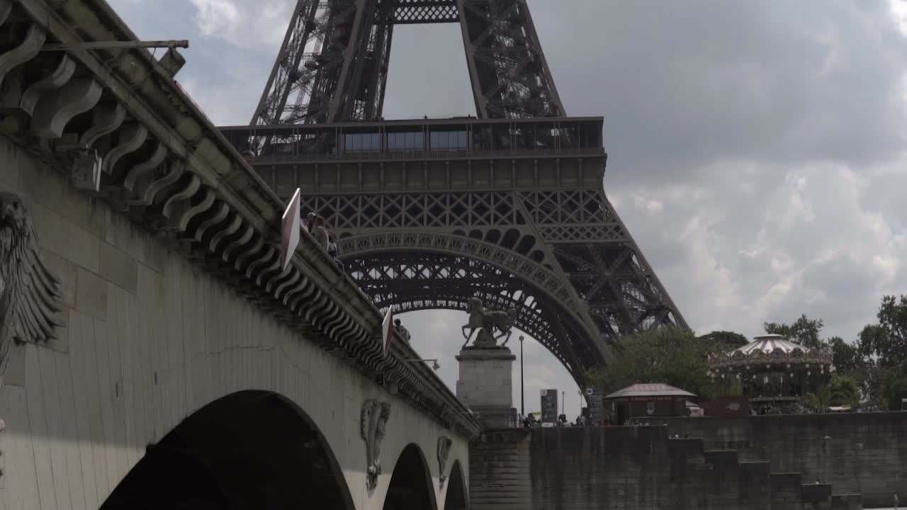 SLOW MOTION: Bottom of Eiffel Tower of Paris appears behind bridge on Boat cruise