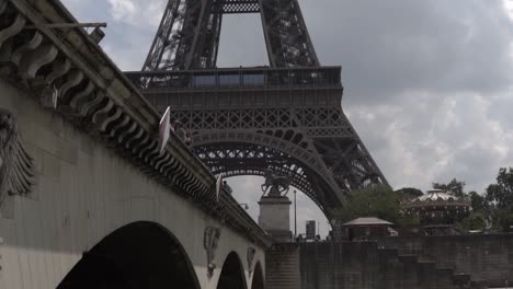 cámara lenta: la parte inferior de la torre eiffel de parís aparece detrás del puente en un crucero en barco