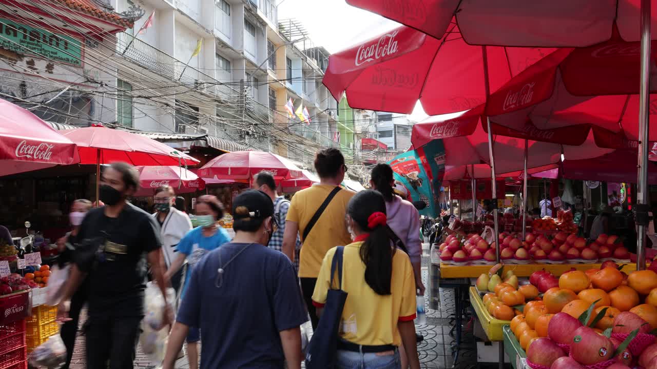 calle de mercado llena de gente con paraguas y puestos de colores
