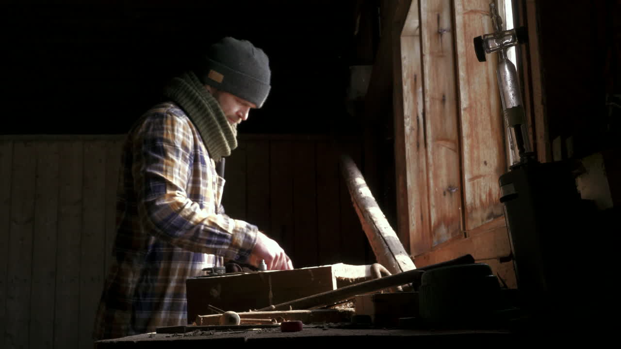 Håndværker inspicerer arbejdsredskaber i lyset fra vinduet