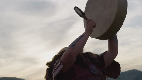 Man-with-closed-eyes-plays-shamanic-drum-with-furry-stick