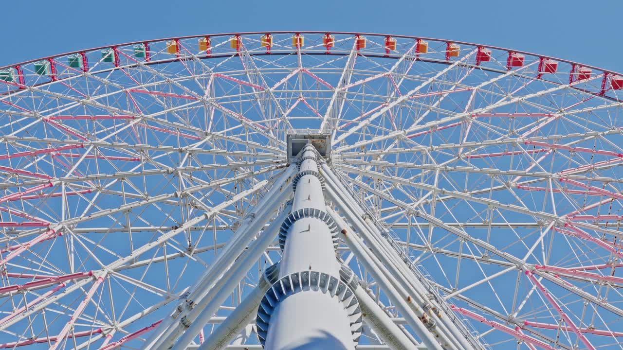 Dramatic low-angle view looking directly up the central support column and massive white structure of a large Ferris wheel