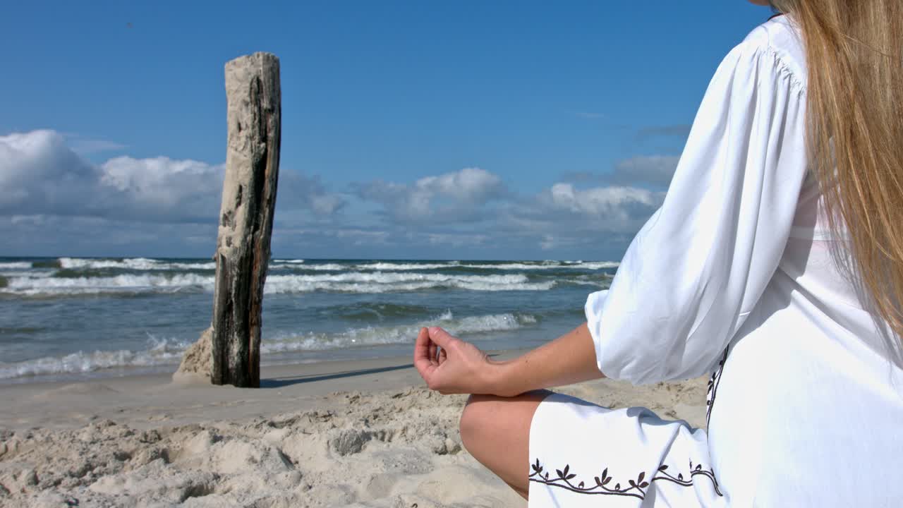 Woman meditating on the beach in the lotus position.