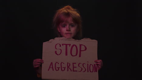 Afraid-dirty-faced-homeless-poor-girl-showing-banner-with-inscription-massage-Stop-Aggression