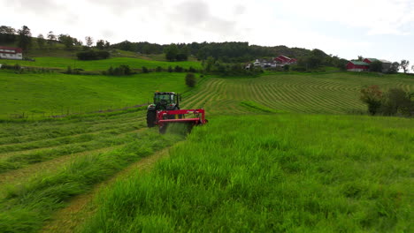 Low-aerial-tracking-behind-tractor-and-mower-conditioner-cutting-down-lush-grass