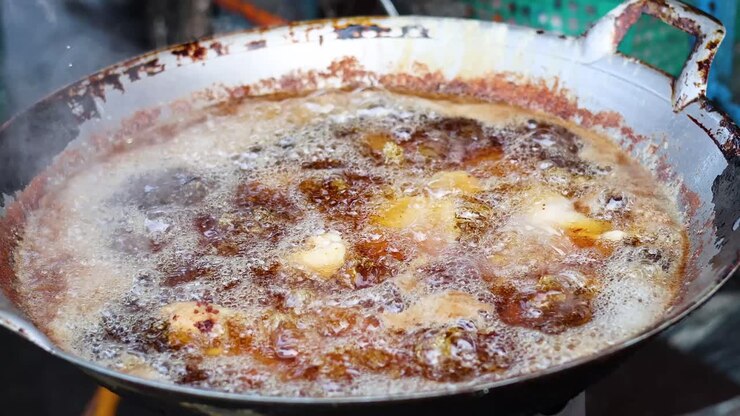 hühner in heißem öl in einer pfanne braten