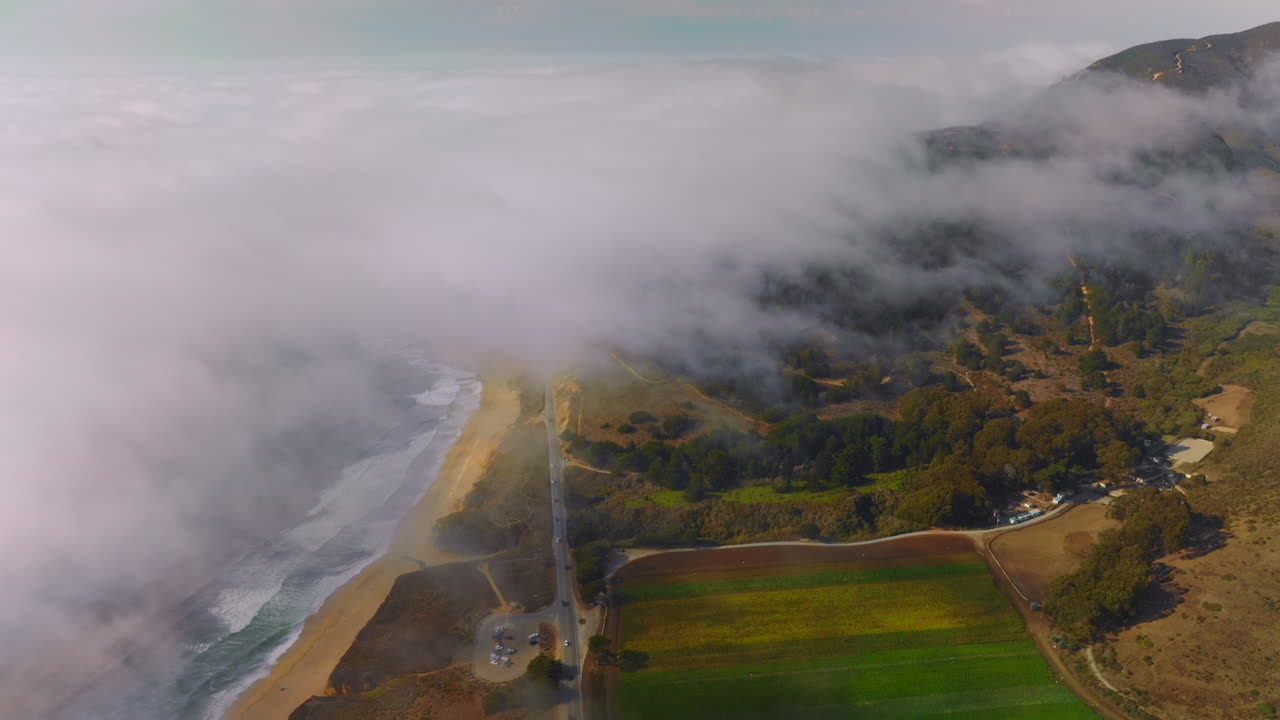 Beautiful coast with sandy beach, rocks and meadows in Montara, California, USA. Thick white fog spreading on the land from water. Aerial view.