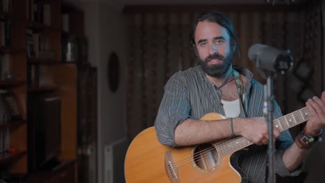 hombre tocando la guitarra acústica en casa