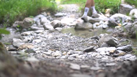 Die-Beine-Eines-Wanderers-Bewegen-Sich-Auf-Einem-Felsigen-Pfad-Voran-Und-Springen-über-Einen-Kleinen-Fluss