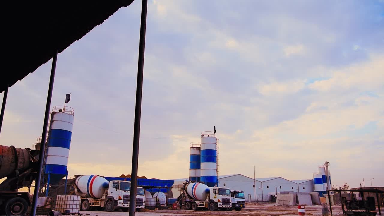 Establishing cinematic push in shot construction site fully equipped with Traktor, trucks, and concrete mixer trucks