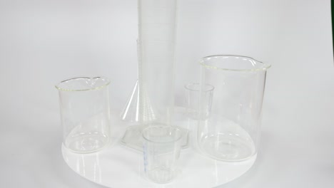 Various clear beakers and cylinders on a white surface