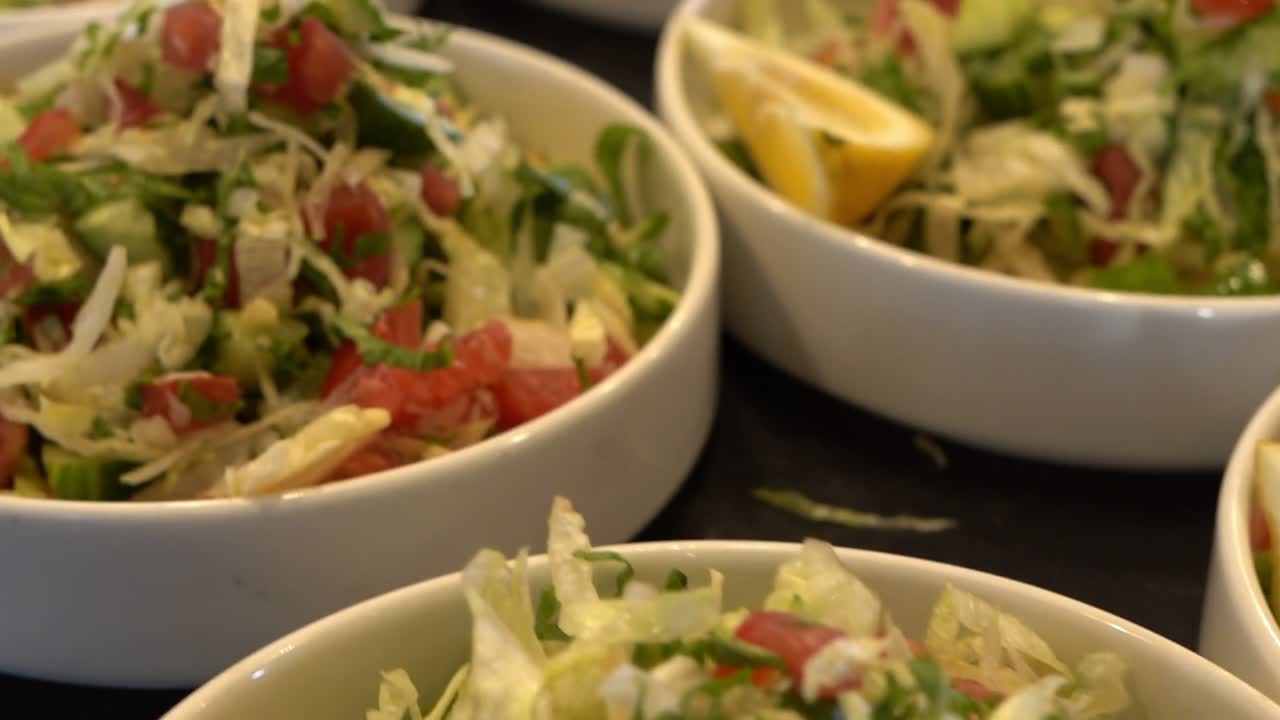 Fresh vegetable salad served in bowls with lemon slices on the side, close up shot