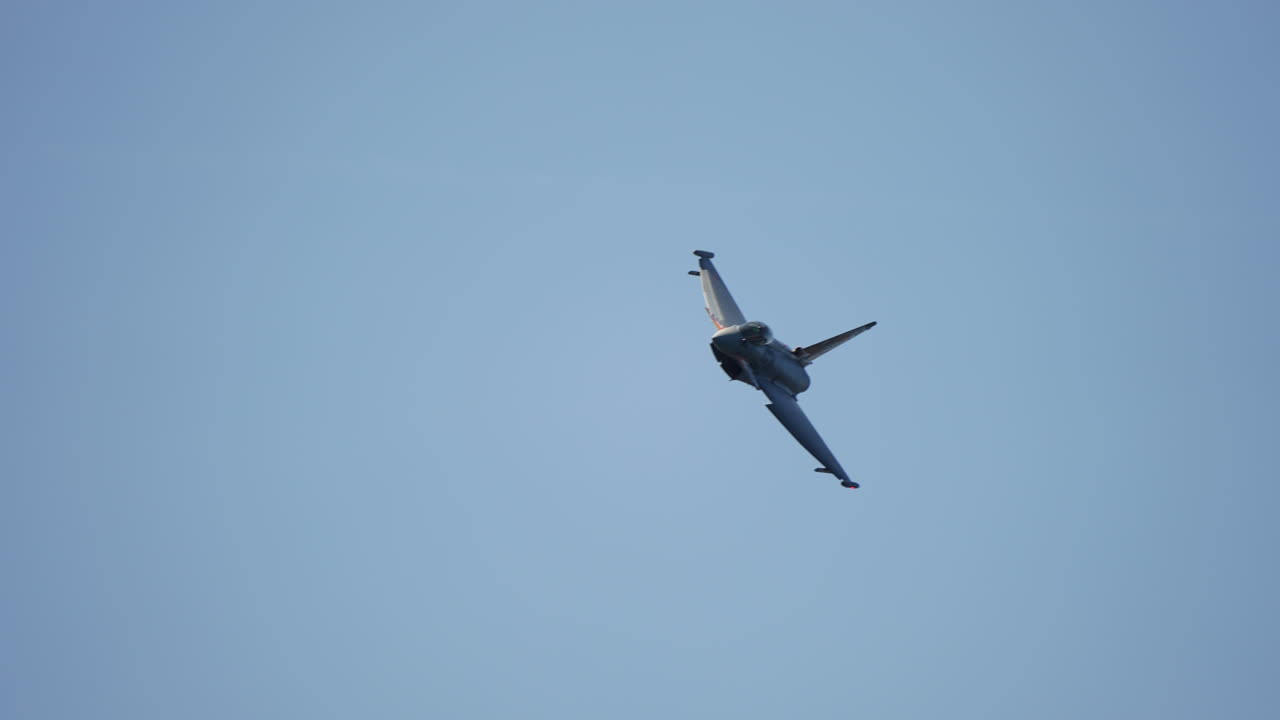 Military jet approaching camera while banking left with visible canopy filmed in slow motion